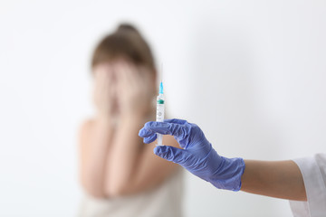 Doctor holding syringe with chickenpox vaccine and scared child on background, closeup. Varicella...