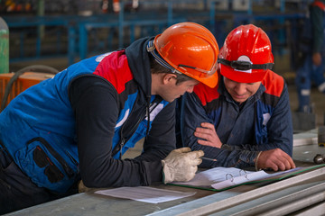 Builders study blueprints at a construction site.