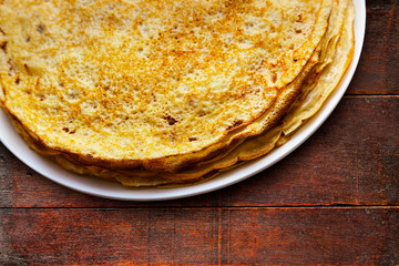 Homemade pancakes on a white plate on a wooden table