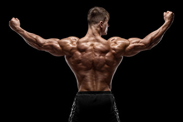 Obraz premium Muscular man showing back muscles, isolated on black background. Strong male rear view