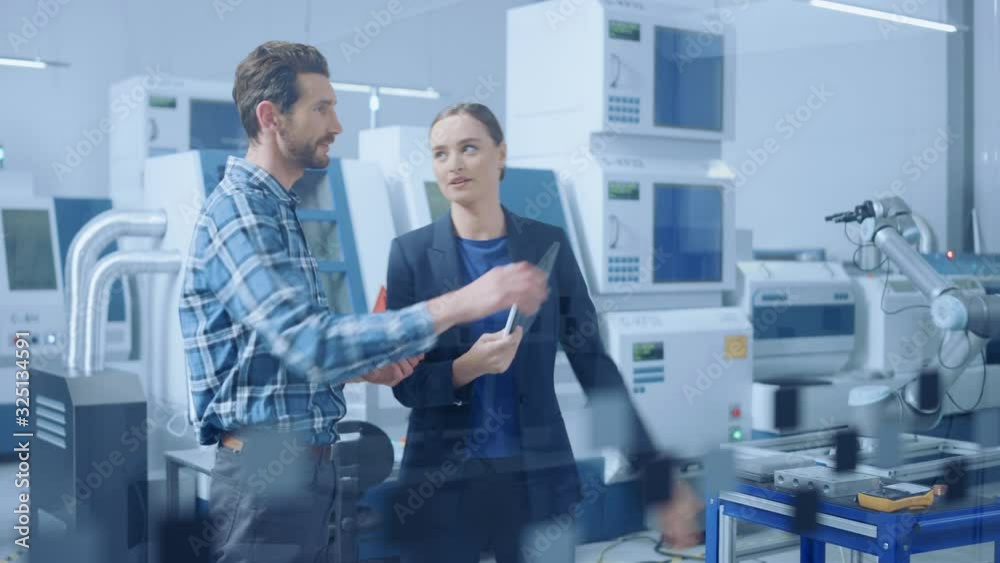 Poster Modern Factory: Female Project Manager and Male Engineer Standing, Talking, Using Digital Tablet for Programming and Monitoring Assembly Line with Robot Arm. Industry 4.0 Facility with CNC Machinery