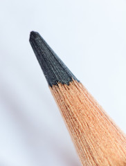 Single black wooden color pencil close up on white background; extreme close up; macro shot; shallow depth of field