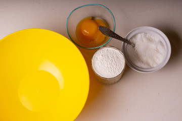 Ingredients for homemade pie stand on the table. Flour, sugar and egg. Close-up.