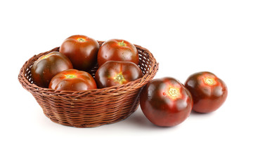 Dark tomatoes on wicker plate