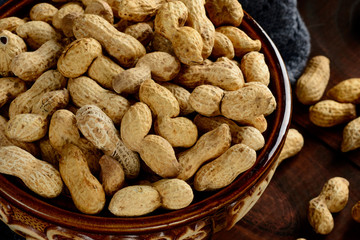 Peanuts in a bowl on the dark background. Peanuts in a shell. Healthy food.