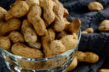 Peanuts in a bowl on the dark background. Peanuts in a shell. Healthy food.