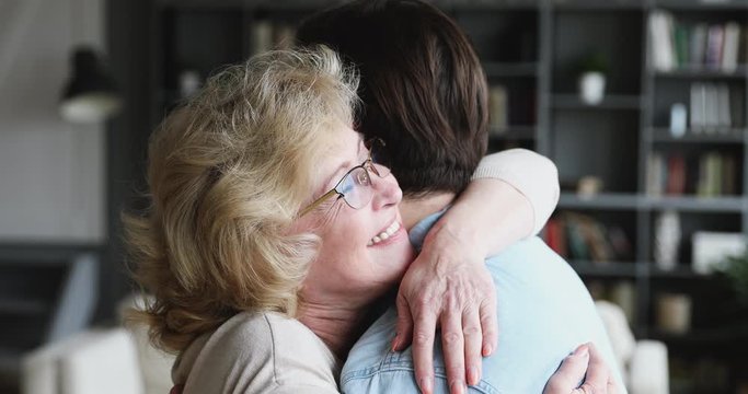 Caring mature old mum hugging adult son expressing mothers love