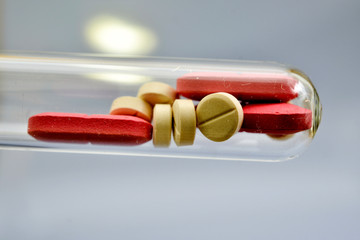 red and white pills in a dusty test tube