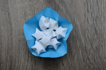  White origami lucky stars wiht paper bowl on wooden