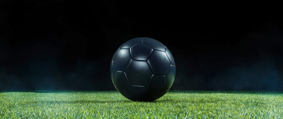 Black Football on an illuminated empty sports field at night.