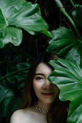 closeup beautiful asian woman be-hide big green leaf