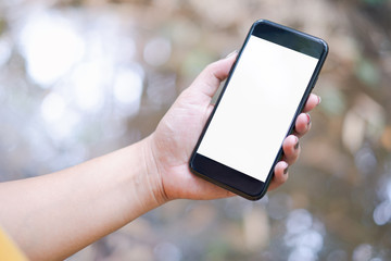 hand holding and using a mobile phone with white blank screen against bokeh of nature background
