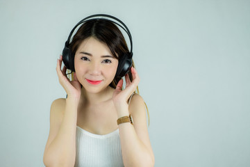 Portrait of beautiful asian woman with headphones listening to music.  happy, smiling / Caucasian female model isolated on white background.