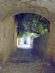 typical quiet cobbled street in rhodes town with an a stone arch and old buildings
