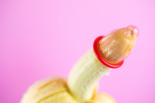 closeup condom on banana with pink background (World AIDS Day concept), soft focus.