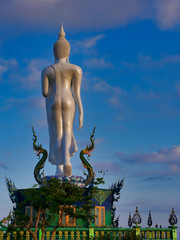 Photo of the big standing buddha statue in buddhist temple of Thailand.