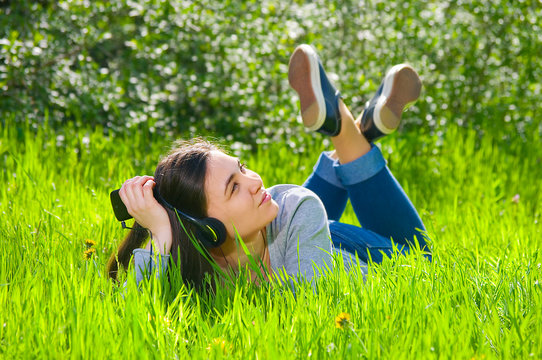 Beautiful young female girl listening to music on the player on the phone talking with headphones in the park on the nature