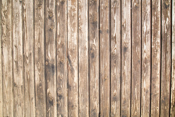 Fototapeta premium The background of the fence is made of old planed dark boards with a pronounced wood structure located vertically, texture design.