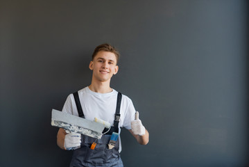 A man in overalls holds a spatula in his hand