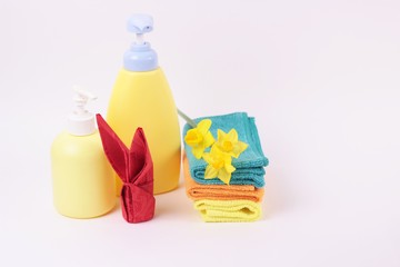 Fototapeta na wymiar Spa and bath concept. Beautiful easter spa composition in yellow color on white background. Boatles, multicolored towels, red bunny from napkin and flower. Copy space for text.