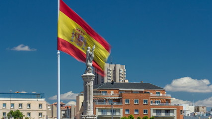 Spanish flag waves behind statue of Christopher Columbus timelapse, plaza de Colon in Madrid, Spain