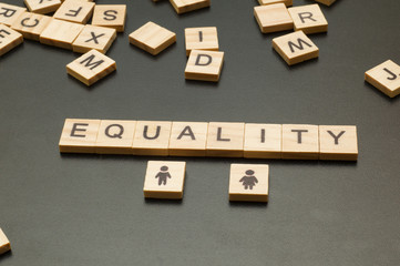 Wooden figures on black background. Gender equality concept. 