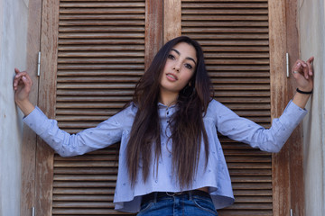 Portrait of pretty caucasian young woman posing, wearing longsleave shirt and jeans with dark hair, winter clothing.