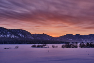 Winter mountain landscape. Orange-purple winter sunset in the mountains. Russia. Republic of Altai.