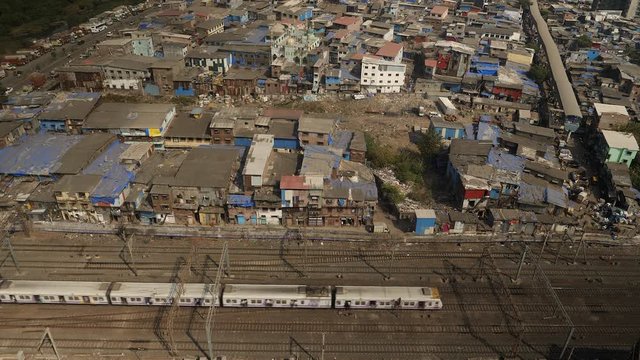 Trains passing slums in Mumbai, India. Aerial view.
