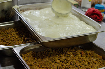 Fototapeta premium moussaka preparation bechamel in dish minced meat close up
