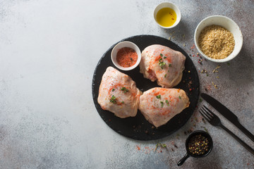 Raw chicken thighs on a black stone plate