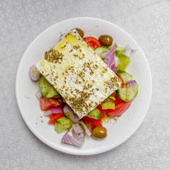 original feta cheese in Greek salad plate, top view close up