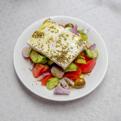 original feta cheese in Greek salad plate, top view close up