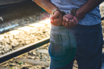 Behind the male criminals he was arrested and handcuffed, with locomotive on the plartform...