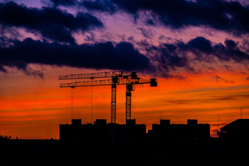 picturesque landscape with sunset with construction cranes on the horizon