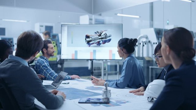 Modern Factory Office Meeting Room: Diverse Team of Engineers, Managers and Investors Talking at Conference Table, Watching Interactive TV that shows Sustainable and Renewable Green Energy Engine