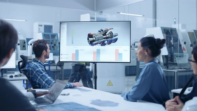 Modern Factory Office Meeting Room: Diverse Team of Engineers, Managers and Investors Talking at Conference Table, Watching Interactive TV that shows Sustainable and Renewable Green Energy Engine