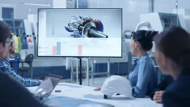 Modern Factory Office Meeting Room: Diverse Team of Engineers, Managers and Investors Talking at Conference Table, Watching Interactive TV that shows Sustainable and Renewable Green Energy Engine