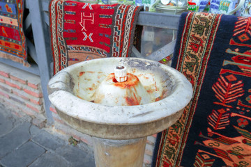 old stone drinking fountain and carpets on the background of  window of a souvenir shop in Tbilisi,...