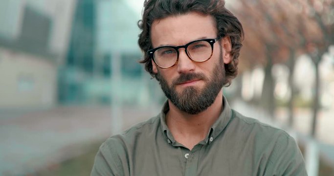 Portrait of Handsome Man standing in front of Camera, posing on it on warm Autumn day. Pleasant weather. Attractive man with Eyeglasses and well groomed Hairstyle. Man with nice Appearance.