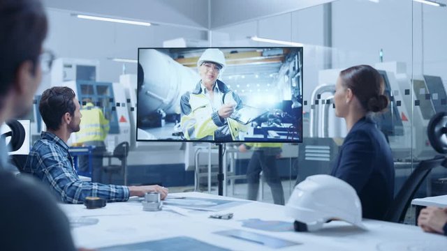 Diverse Group of Specialists, Managers in the Factory Office Meeting Room, Have Conference Video Call with Factory Chief Female Engineer, She Talks about Production Growth, Uses Tablet Computer