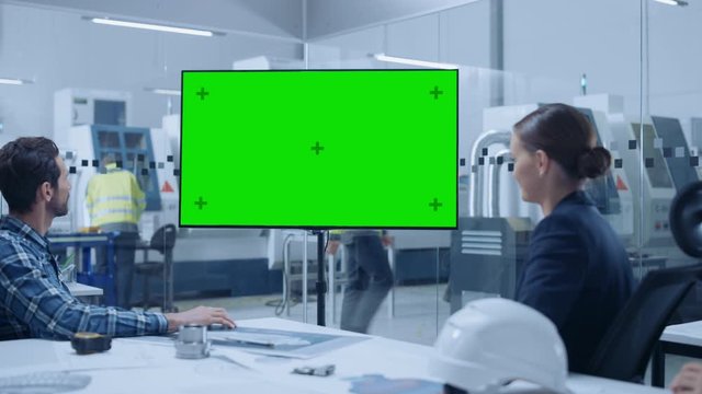 Modern Factory Office Meeting Room: Diverse Team of Engineers, Managers and Investors Talking at Conference Table, Watching Interactive TV that shows Green Screen Chroma Key Mock-up