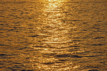 Beautiful background in gold color. Natural texture of sea water, illuminated by setting sun. Montenegro, Adriatic Sea