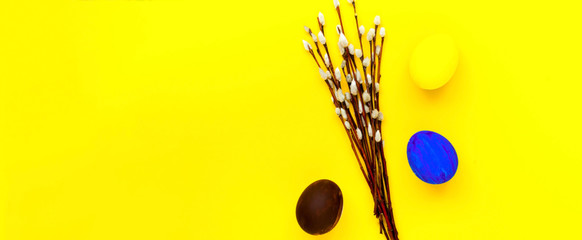 Fototapeta premium Colorful easter eggs and willow branches on yellow background. Festive concept, minimalism. Close-up