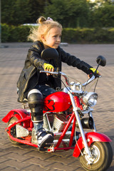 Fototapeta na wymiar biker child girl on a red motorcycle in a leather jacket and bright motorcycle gloves