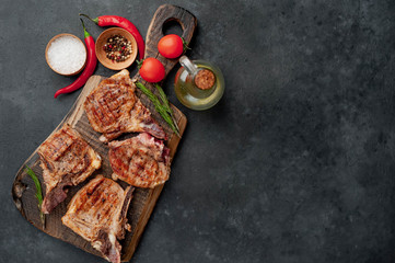 grilled beef steaks with spices on a cutting board on a stone background with copy space for your text