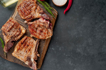 grilled beef steaks with spices on a cutting board on a stone background with copy space for your text