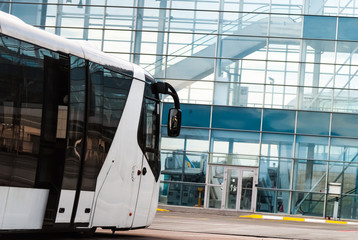 White modern tour bus and glass building. Shuttle bus in the airport.