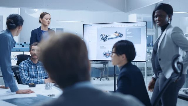 Modern Automotive Factory Office Meeting Room: Diverse Team of Engineers, Managers and Investors Talking at Conference Table, Watching Interactive TV that shows Green Energy Electric Car Concept