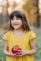 Child picking apples on farm in autumn orchard. Loss of milk tooth smile. Healthy nutrition.